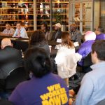man speaks to group seated at table