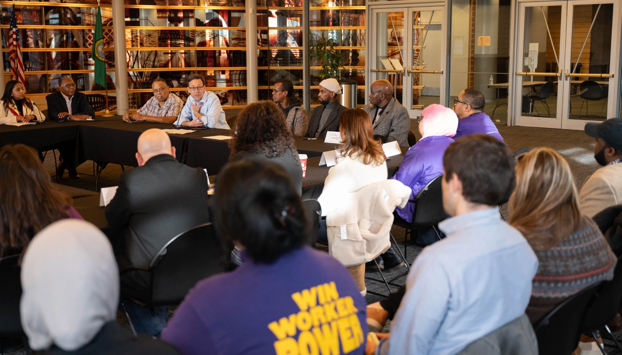 man speaks to group seated at table