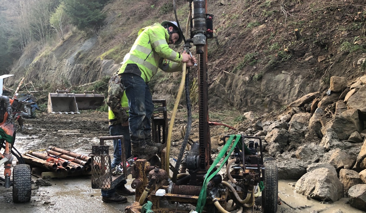 Worker operates drilling equipment to install steel dowels into hillside above I-5 northbound closure near Lake Samish following landslide