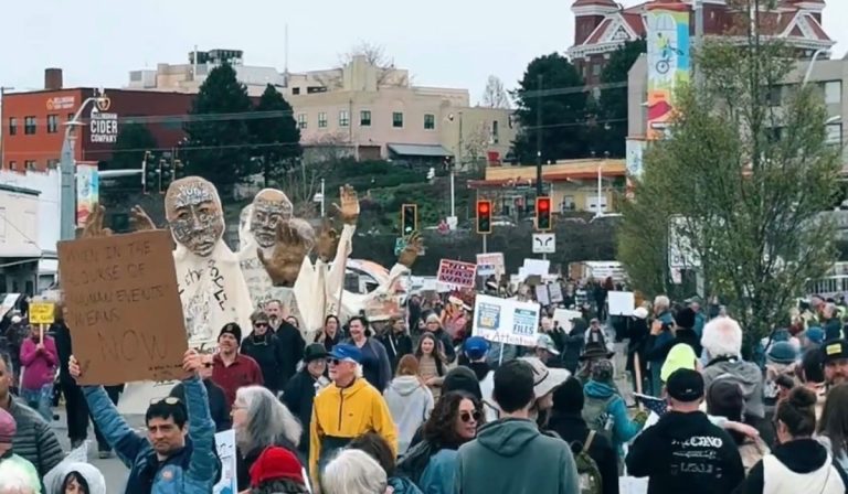 Thousands of protesters march through downtown Bellingham, Washington, during the No Kings Day of Action on March 28, 2026, carrying signs and large puppet figures