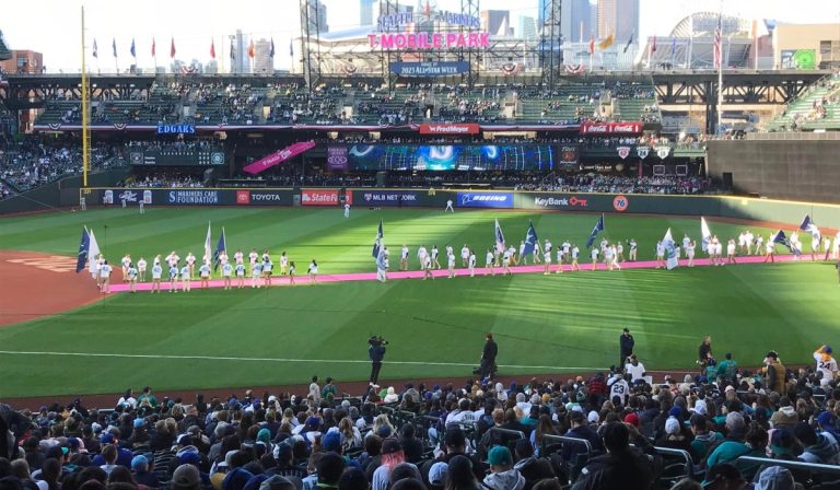 Wide view of Opening Day 2023 at T-Mobile Park in Seattle, with players and participants lined up across the outfield during pregame ceremonies as a packed crowd fills the stands.