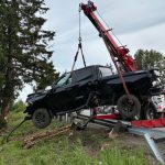 A black pickup is lifted by a tow crane.