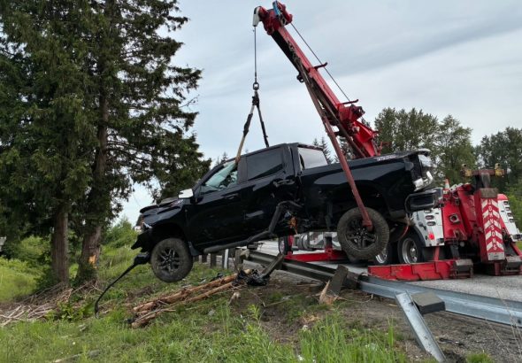 A black pickup is lifted by a tow crane.