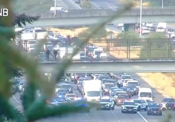 All lanes of I-5 near Everett were briefly closed after a man climbed onto an overpass ledge Friday morning. He was arrested afterward.