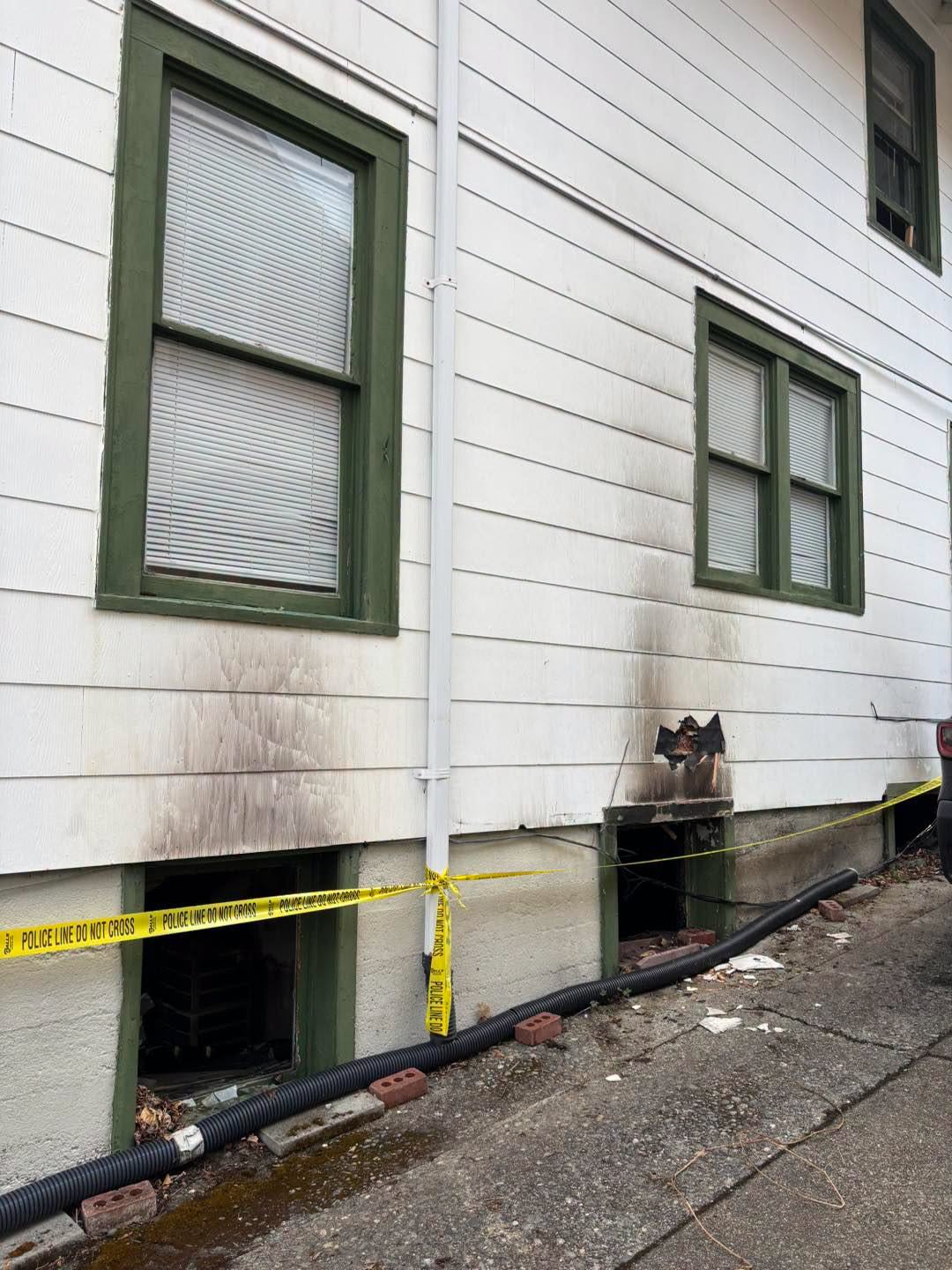 Exterior view of the Bellingham home showing smoke damage above two basement windows