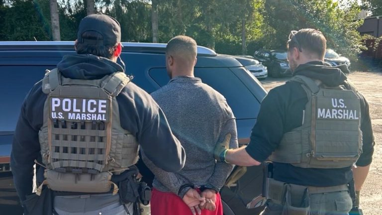 U.S. Marshals take Zealand Adams into custody in Kent, one of two coordinated arrests connected to an alleged home invasion in Alabama.