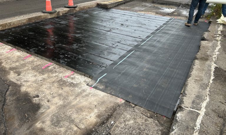 Crews stand on wet stabilization fabric on the bridge deck as paving work on the Klein Ditch Bridge came to a standstill Friday.