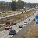 A Washington State Patrol trooper and WSDOT incident response crew work the scene along northbound I-5 as traffic passes by. A separate vehicle was also pulled over by WSP in the area at the time.