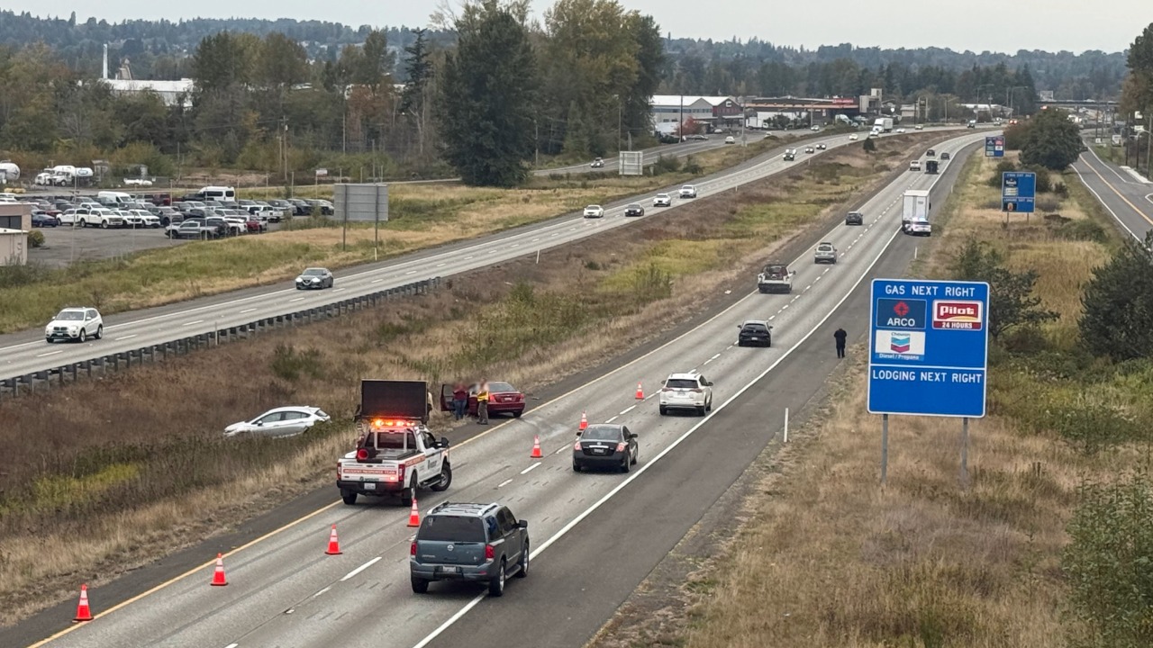 A Washington State Patrol trooper and WSDOT incident response crew work the scene along northbound I-5 as traffic passes by. A separate vehicle was also pulled over by WSP in the area at the time.